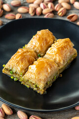 Pistachio baklava on a wooden background. Turkish style pistachio baklava presentation and service. Vertical view. close up