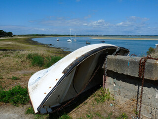 Boat tipped on the dry with metal chains and harbor in the background, France