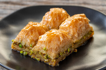 Pistachio baklava on a wooden background. Turkish style pistachio baklava presentation and service. Horizontal view. close up