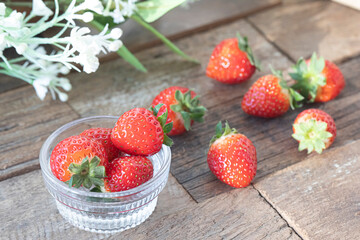 Fresh strawberries in a bowl on wooden table.