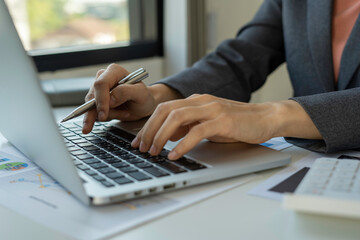 businesswoman is typing on the keyboard of laptop for check electronic mail, preparation of presentation in a meeting, get information for shopping online or operation of internet banking