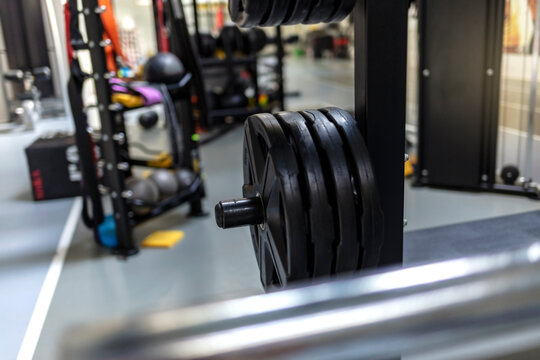 Various indoor weight lifting training equipment. Dumbbells in a row at gymnasium or health club interior. Heavy workout equipment designed for cross-training and weight exercise at health club studio