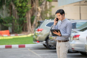 Car insurance claim staff calling and holding a clipboard in the parking area