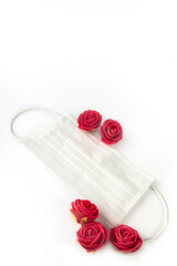 Red roses and a protective medical face mask isolated on white background. Safe Valentine's Day during the coronavirus pandemic. Covid-19 and Valentine concept