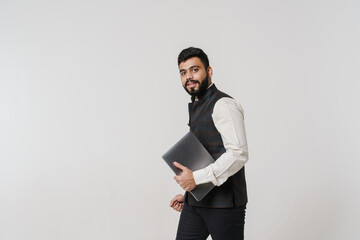 Bearded south asian man wearing vest posing with laptop