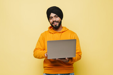 Bearded south asian man wearing turban using laptop