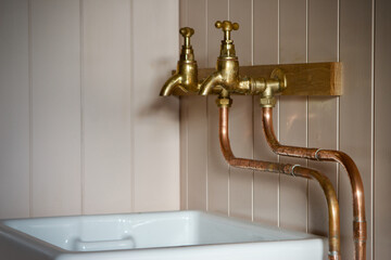 vintage brass faucet taps wall mounted above a white butler sink