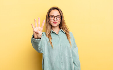 pretty caucasian woman smiling and looking friendly, showing number four or fourth with hand...
