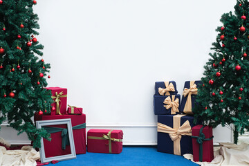 Backdrop christmas background two christmas tree with gift box present on white wall. Indoor living room decoration. New year winter holiday concept.
