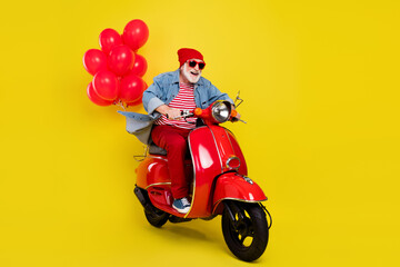 Portrait of elderly retired pensioner cheerful man riding moped having fun isolated over vivid yellow color background