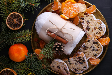 Classical Stollen is a Traditional German Cake with raisins and tangerines on dark background. Fruit cake for the Holiday.