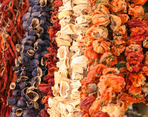 Dried vegetables in the traditional way strung on threads and hung on the street. Dried red hot and sweet peppers, eggplant