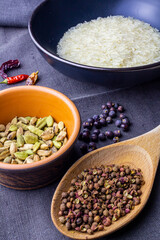 Rice bowl with cardamon, chilli and sichuan paper on dark cloth with juniper berry