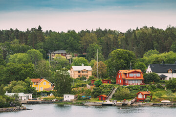 Sweden. Beautiful Red And Yellow Swedish Wooden Log Cabins Houses On Rocky Island Coast In Summer...