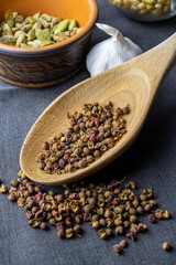 cardamon clay pot, sichuan paper in wood spoon, chilli paper and juniper berry with garlic and corn in glass jar