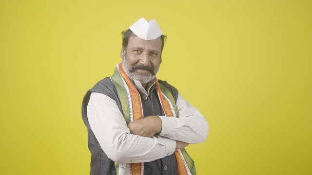 Confident senior politician looking at camera by crossing arms on yellow background - concept of positive expression and successful lawmaker or leader