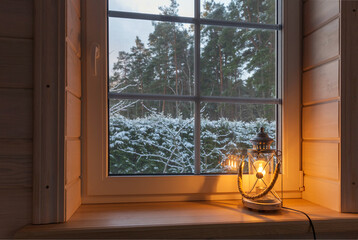 Festive lantern on a wooden window sill in winter indoors.