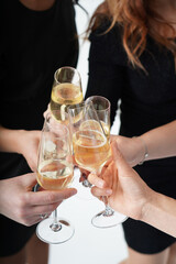 hands of women in black cocktail dresses with glasses of champagne close-up. hen-party