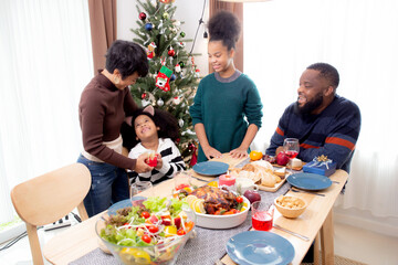 Happy family with mother giving gift box with daughter during dinner at home, celebration in xmas with parent surprising children with enjoyment at house, thanksgiving eve, Merry Christmas.