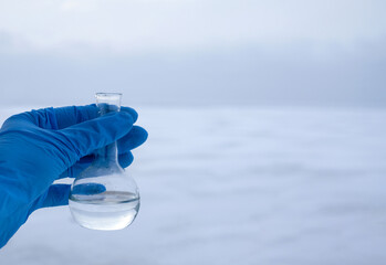 Hand in glove holding water sample from the frozen sea, water diversion, ecology concept. Copy space