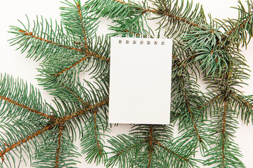 White notebook on a spruce branch. Place for your text