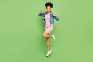 Full length photo of cool young lady jump show thumb up wear dress shirt sneakers isolated on green background