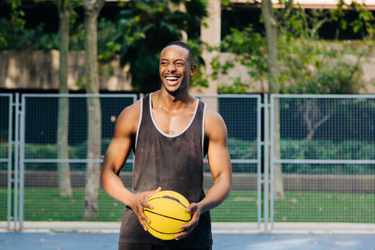 Happy black basketball player holding ball