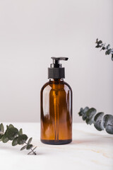 Amber glass cosmetic bottle with eucalyptus leaves. Natural no plastic concept. 