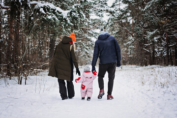 Outdoor family activities for happy winter holidays. Happy father and mother playing with little baby toddler girl daughter in winter park, forest. Happy family on winter weekend, Christmas holidays