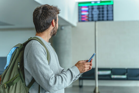 Traveler with phone near airport digital signage