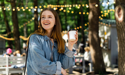 A woman smiles at a young hipster walking in the park, and drinking coffee.