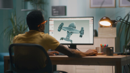 Black man using computer and creating 3D model of futuristic aircraft for videogame or movie while working from home - obrazy, fototapety, plakaty
