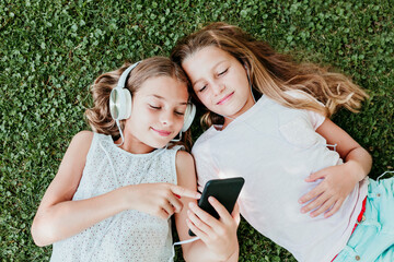 Smiling friends listening music while lying on grass in summer