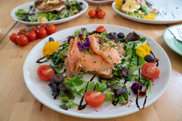 Danish open sandwich Smorrebrod with salmon on rye bread with vegetables and herbs
