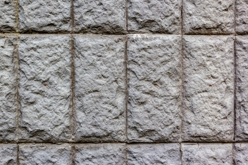 Gray background of imitation stone masonry tiles for exterior walls of buildings and structures. Decorative wall of artificial stone in grey tones in geometric pattern as background or texture