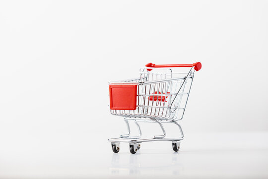 Metallic shopping cart trolley on light gray background with copy space