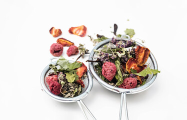 Dried tea leaves and berries in tea strainer. Composition with organic, natural herbal tea and dry berry on white desk.