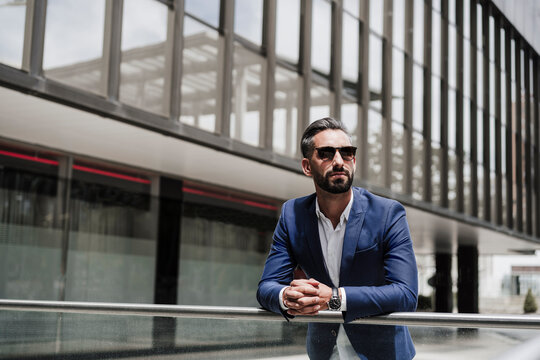 Male entrepreneur with sunglasses leaning on railing