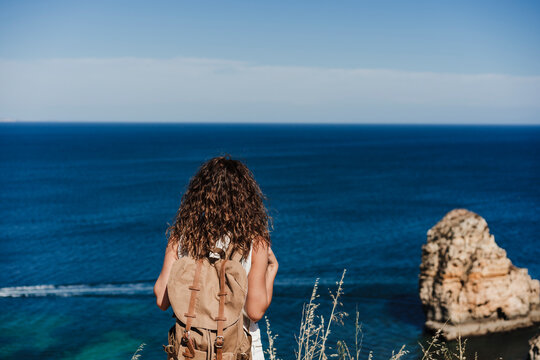 Female backpacker looking at sea on sunny day
