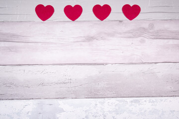Red felt hearts on a background of old wooden planks resembling an old parquet floor. Concept of valentines day and love in general