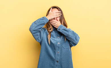 pretty caucasian woman covering face with both hands saying no to the camera! refusing pictures or...