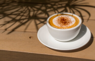 cappuccino coffee in white cup on wooden table