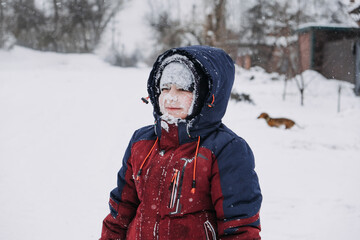 Fototapeta na wymiar Stop Kids from Eating Snow. Outdoor winter portrait of preschooler boy with with a snowy face and tongue hanging out eating snow