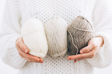 Women's hands hold threads for knitting, made of natural environmentally friendly wool, close-up....