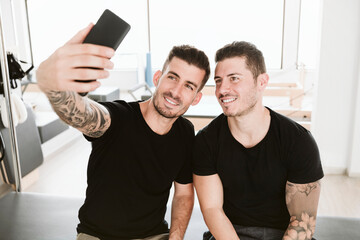 Male instructor taking selfie with man in pilates studio