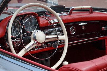 Oldtimer mit rotem Leder Innenraum und weißem Lenkrad mit Radio und Tacho Armaturen