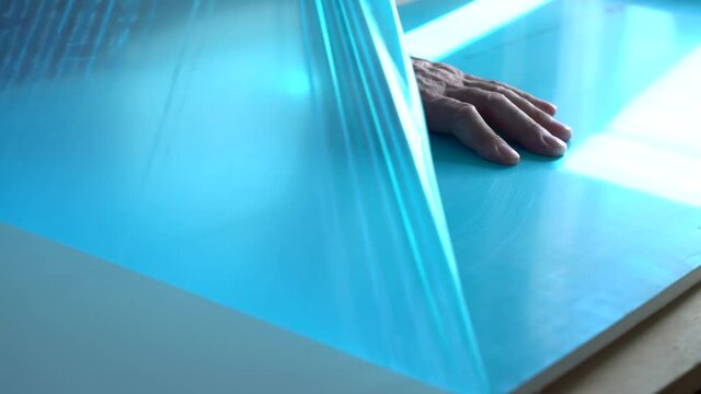 Worker's hands remove the protective film coating