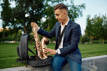 Male saxophonist takes the saxophone from the case
