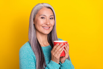 Portrait of attractive cheery grey-haired woman drinking tea copy space isolated over bright yellow color background