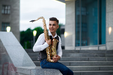 Male saxophonist poses at the stairs on street